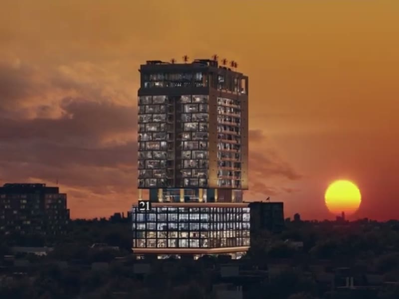 A rendered high-rise against an orange sunset, from a television commercial.